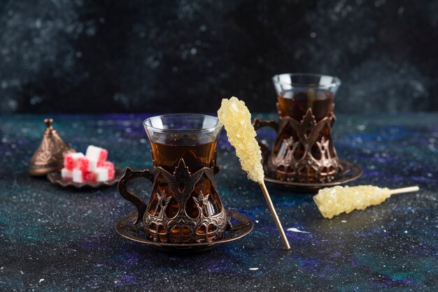 Sweet colorful candies and fragrant tea on blue surface