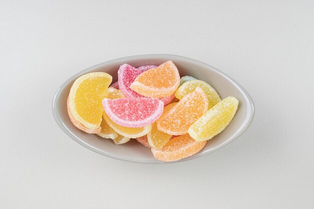 Сладкие красочные желейные конфеты в миске на бежевой поверхности