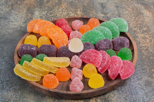 Sweet colorful jelly candy on wooden plate . High quality photo