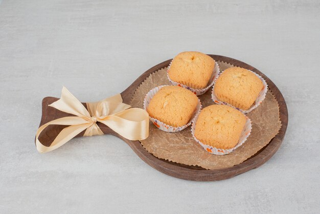 Sweet cookies with cream on wooden plate decorated with ribbon.