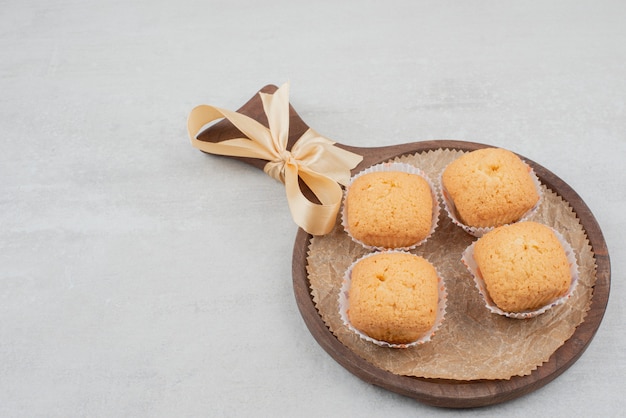 Free photo sweet cookies with cream on wooden plate decorated with ribbon.