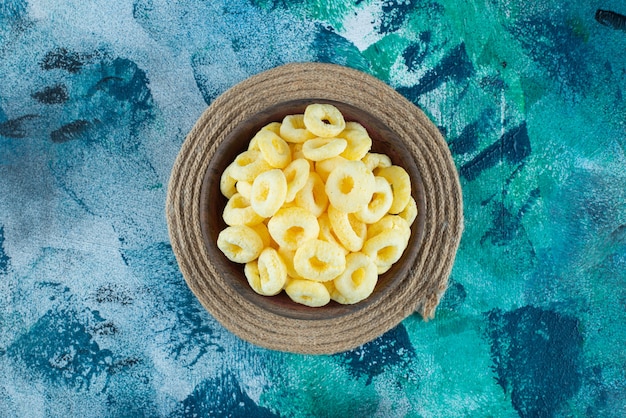 Sweet corn ring in a wooden bowl on trivet, on the marble table.