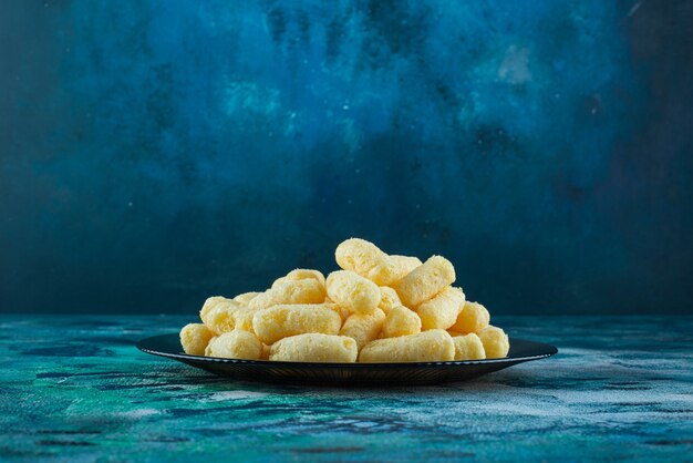 Sweet corn sticks on a glass plate plate on the blue surface