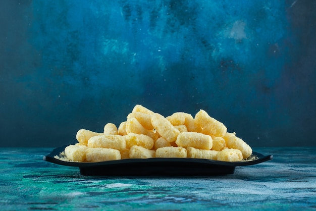 Foto gratuita bastoncini di mais dolce sulla piastra sull'azzurro.