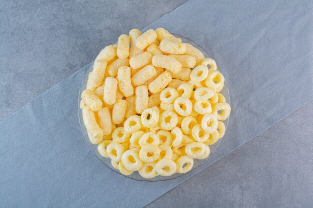 Sweet corn sticks and rings on a pieces of fabric , on the marble surface