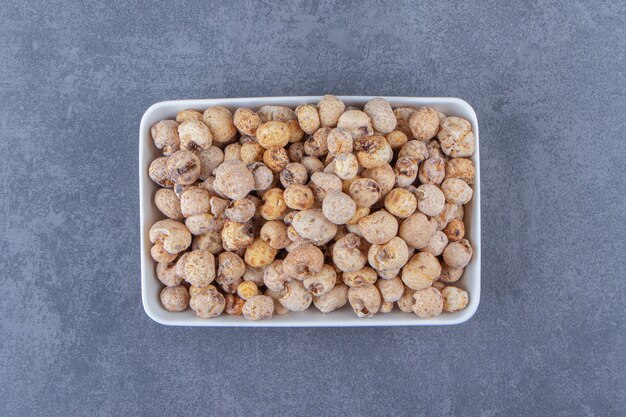 Sweet cornflakes with muesli in a bowl, on the marble background. High quality photo