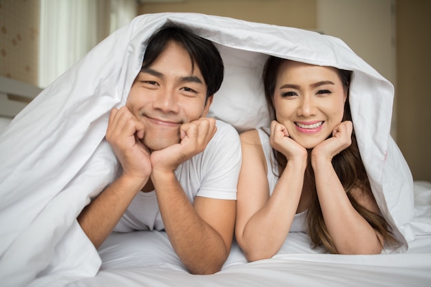 Free photo sweet couple playing under the blanket on the bed