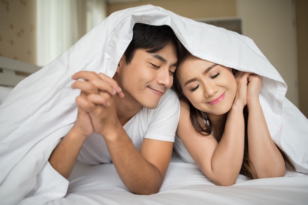 Sweet Couple playing under the blanket on the bed