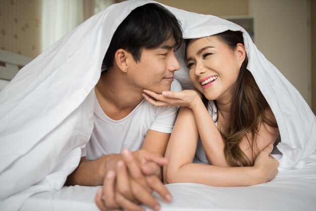 Sweet Couple playing under the blanket on the bed