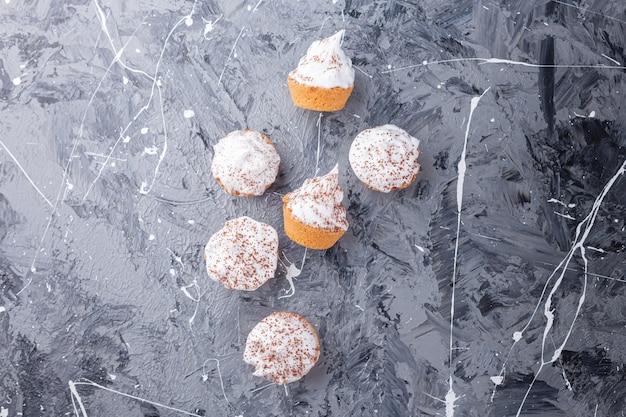 無料写真 大理石の背景に散らばっている甘いクリーミーなミニカップケーキ。