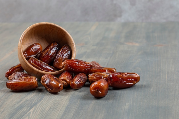 Free photo sweet dates out of wooden bowl on marble surface