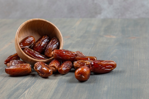 Sweet dates out of wooden bowl on marble surface