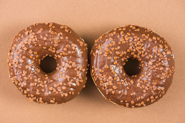 Free photo sweet donuts glazed with sprinkles on brown background