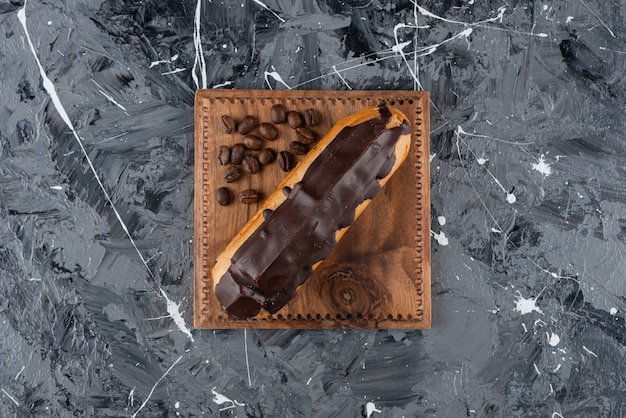 Foto gratuita dolce eclair con glassa al cioccolato posto su una superficie di marmo.