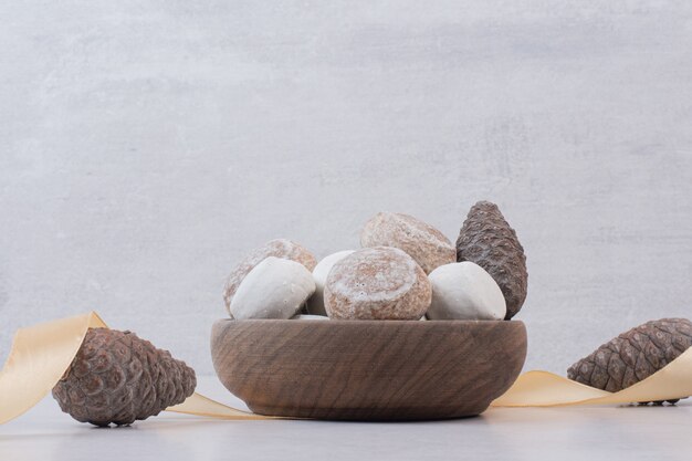 Sweet gingerbread with pinecone on wooden plate .