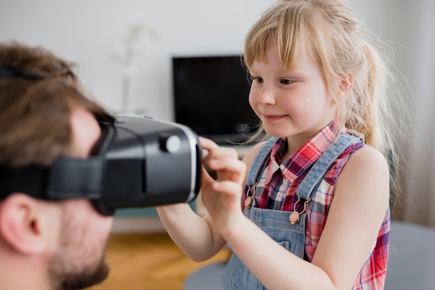 Sweet girl helping father with VR goggles