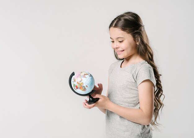 Сладкая девочка держит глобус в студии
