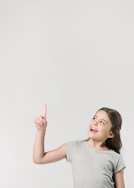 Sweet girl pointing up in studio