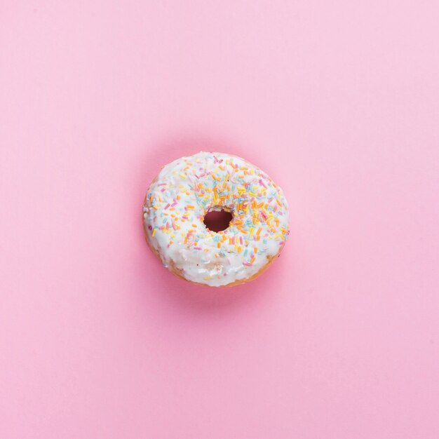 Sweet glazed donut in center of pink background