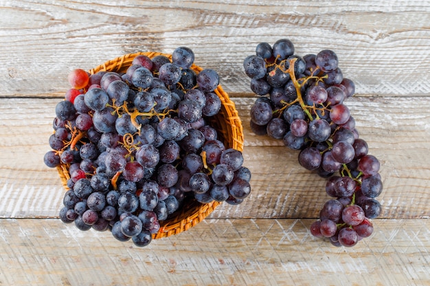 Sweet grapes in a wicker basket on a wooden background. flat lay.