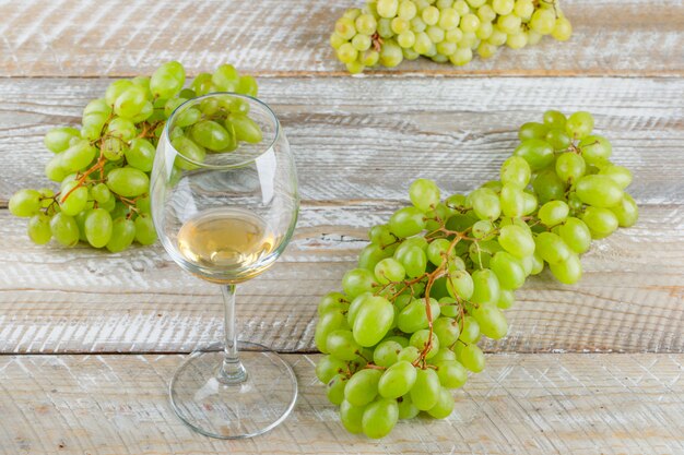 Sweet grapes with drink on wooden background, high angle view.