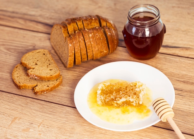 甘いハニカム。テーブルの上のパンと蜂蜜の瓶