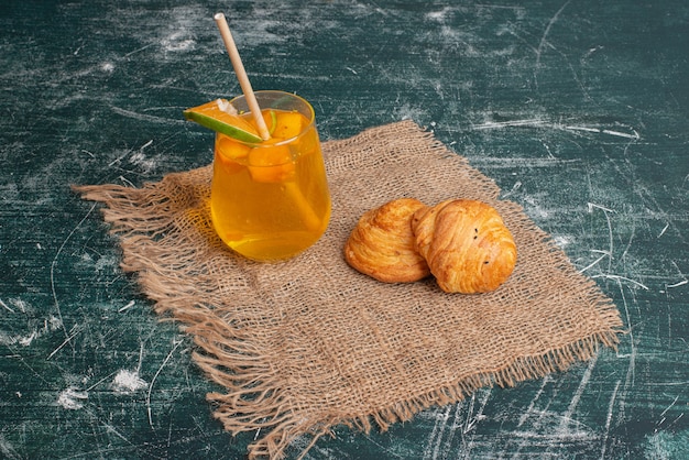 Sweet juice with tasty bakery on marble surface .