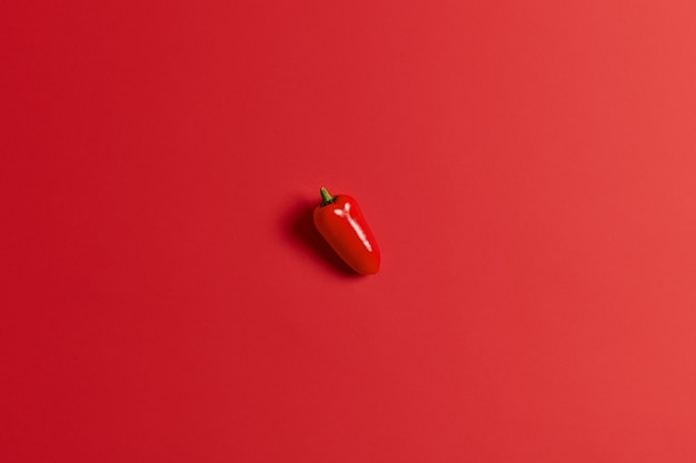 Sweet juicy red bell pepper isolated over bright background. Paprika for preparing delicious salad. Healthy food and fresh vegetables. Closeup and top view. Single vegetable. Autumn harvest.