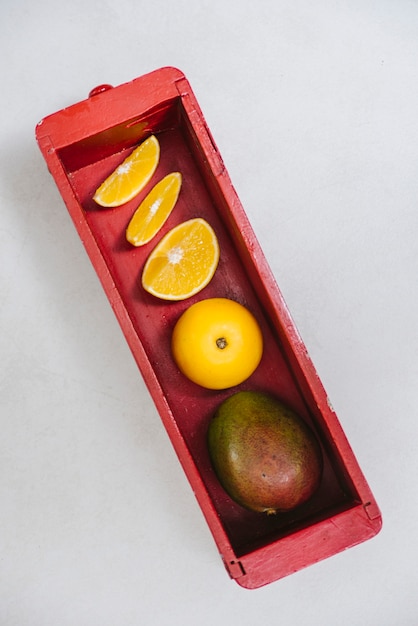 Free photo sweet lime and mango in red wooden container