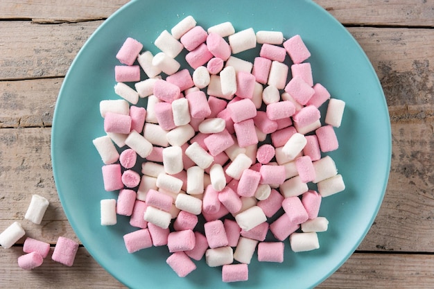 Sweet marshmallows topping in a blue plate on wooden table