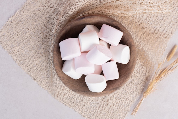 Sweet marshmallows on wooden board on burlap