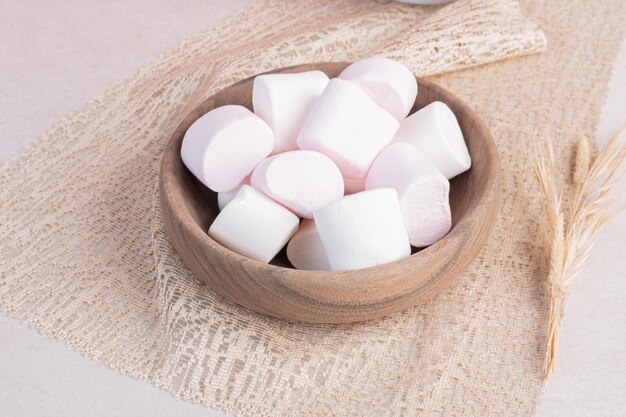 Sweet marshmallows on wooden board on burlap