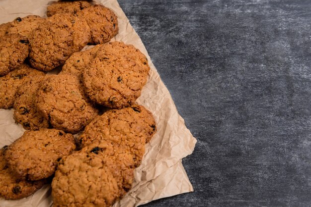 Sweet oatmeal cookies on baking paper at wooden table