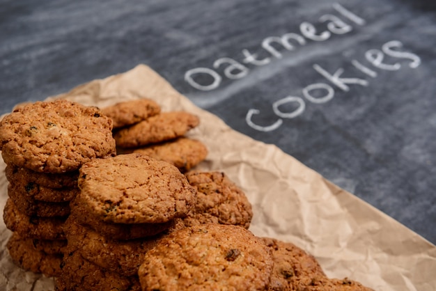 Foto gratuita biscotti di farina d'avena dolci sulla carta di cottura alla tavola di legno