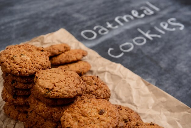 Sweet oatmeal cookies on baking paper at wooden table