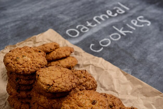 Sweet oatmeal cookies on baking paper at wooden table