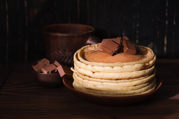 甘いパンケーキチョコレートトッピング。チョコレートの朝食と自家製のパンケーキ。皿の上の朝のデザートココアパンケーキ