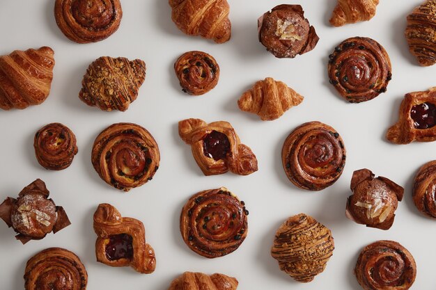 Sweet pastries, croissants, swirls and cupcakes isolated on white background, prepared by special recipe from flour, sugar, ready to sell in bake shop. Delicious confectionery. Junk food concept