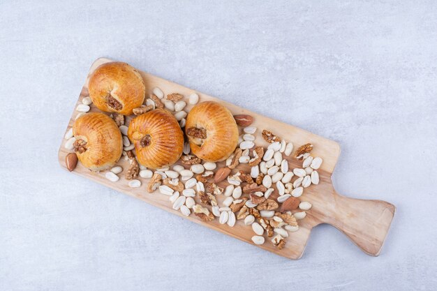 Sweet pastries with kernels on wooden board with various nuts.