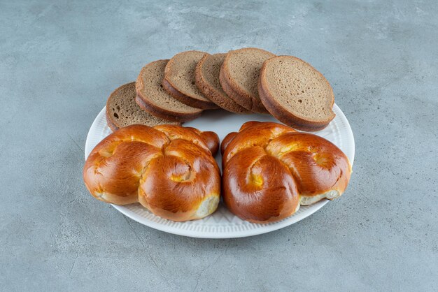 Sweet pastry and bread slices on white plate.