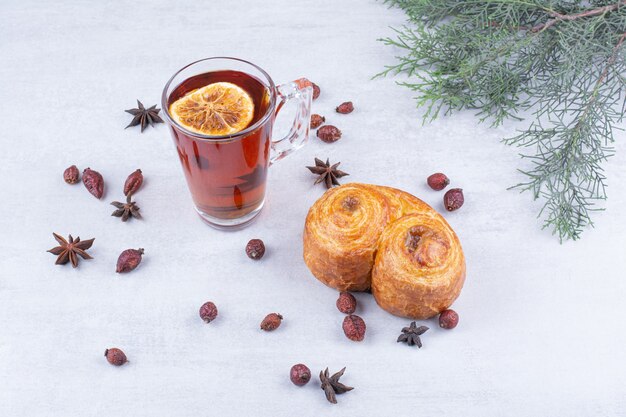 Sweet pastry and glass of tea with rosehips and cloves.