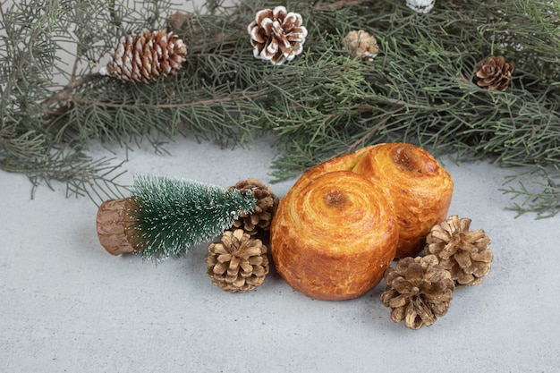 Sweet pastry with Christmas pinecones on white surface