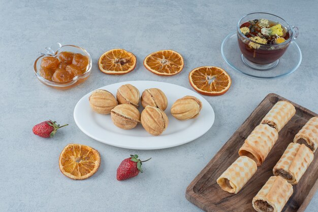 Sweet pastry with dried orange and cup of herbal tea on marble background. High quality photo