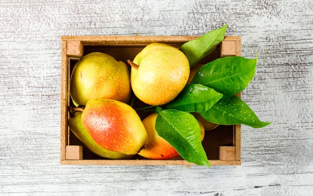 Sweet pears with leaves in a wooden box on grungy grey background