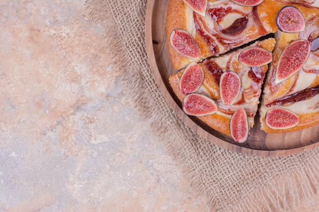 Sweet pie with fig and caramel syrup on a wooden platter.