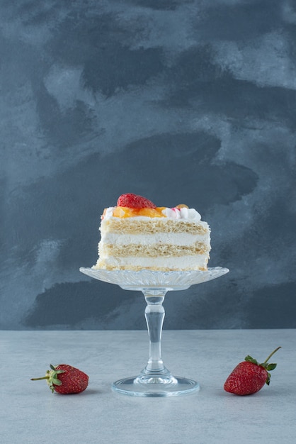 Sweet piece of cake on glass plate and two red strawberry. High quality photo