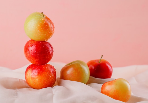 Sweet plums on textile and pink surface