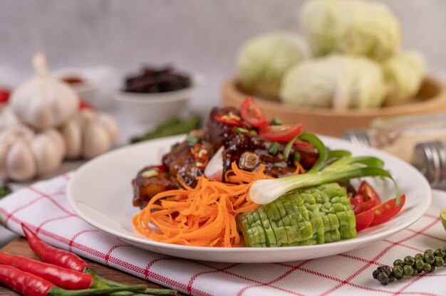 Sweet pork in a white plate with chopped scallions, chili, lime, gourd, tomato and garlic.