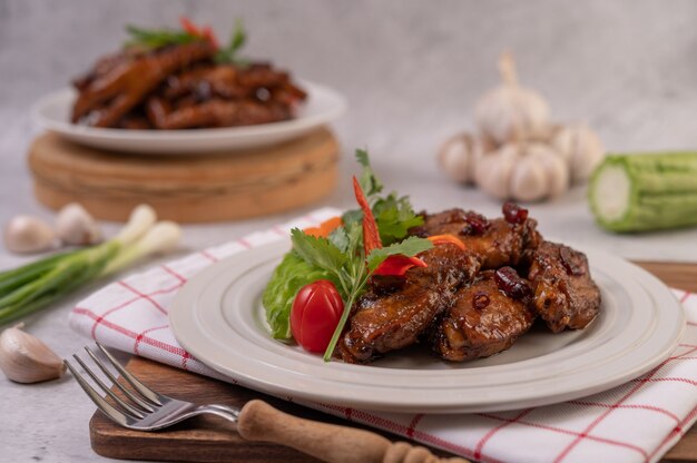 Sweet pork in a white plate with chopped scallions, chili, lime, gourd, tomato and garlic.