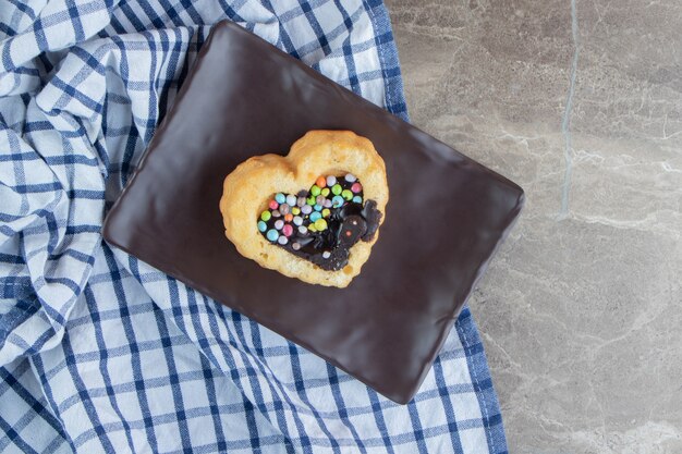 Сладкий слоеный пирог с красочными конфетами на темной тарелке